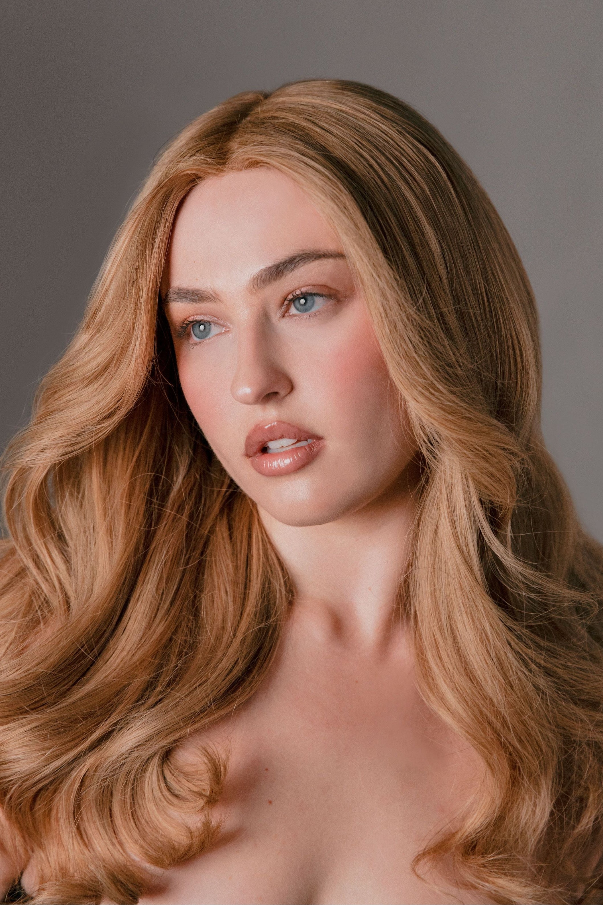 Woman with long, wavy blonde hair against a neutral background