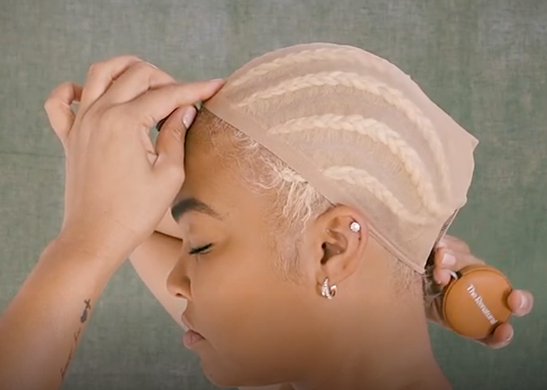 Woman with wig cap measuring her head from nape to forehead using a flexible measuring tape.