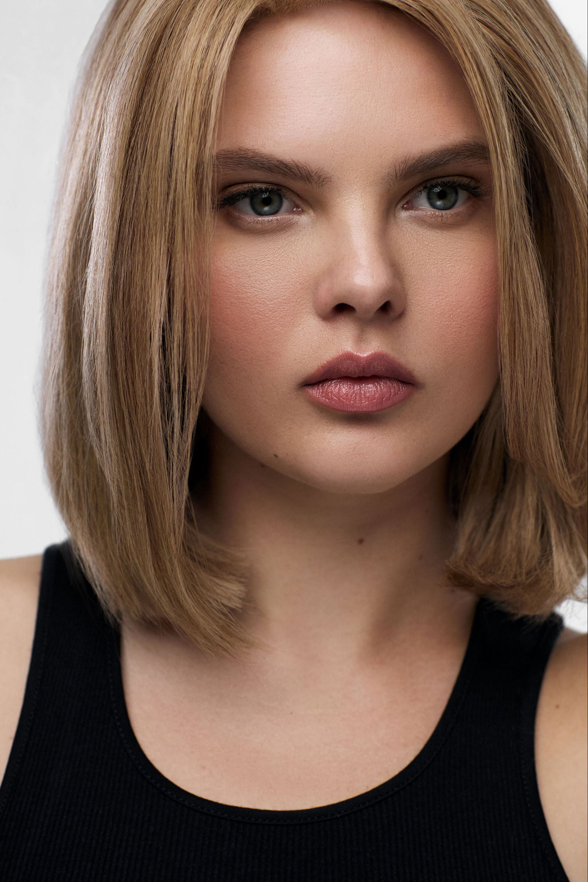 Woman with short blonde hair wearing a black top against a neutral background